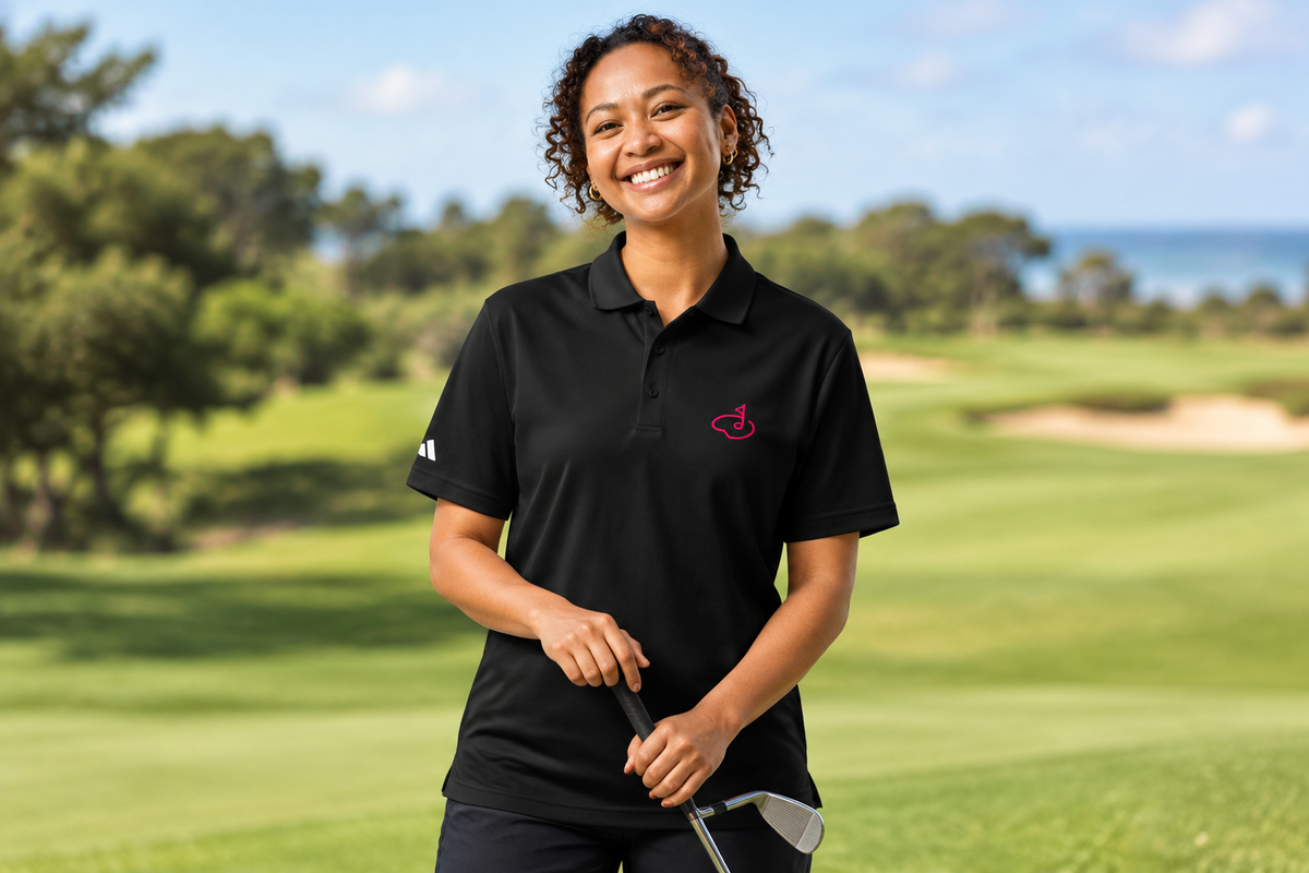 Hat-free woman wearing the black polo with pink chest emblem on a golf course